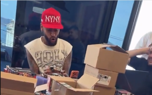 Neymar Pokémon: o jogador durante a live de domingo, de boné vermelho, com as caixas de carta na mesa (Reprodução/Instagram, via CNN Brasil)
